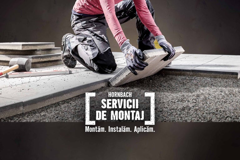 Un muncitor așază pavaj într-un spațiu exterior, folosind un ciocan de cauciuc și o nivelă cu bulă de aer pentru suprafețe plane.