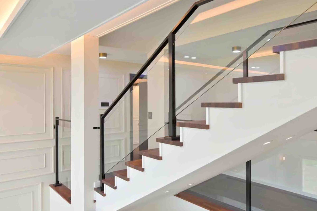 Scară modernă, luminoasă, cu trepte din lemn și balustradă din sticlă cu stâlpi metalici.