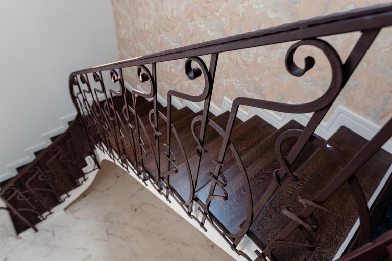 Vedere a unei scări cu trepte din lemn închis la culoare și balustradă metalică artistică