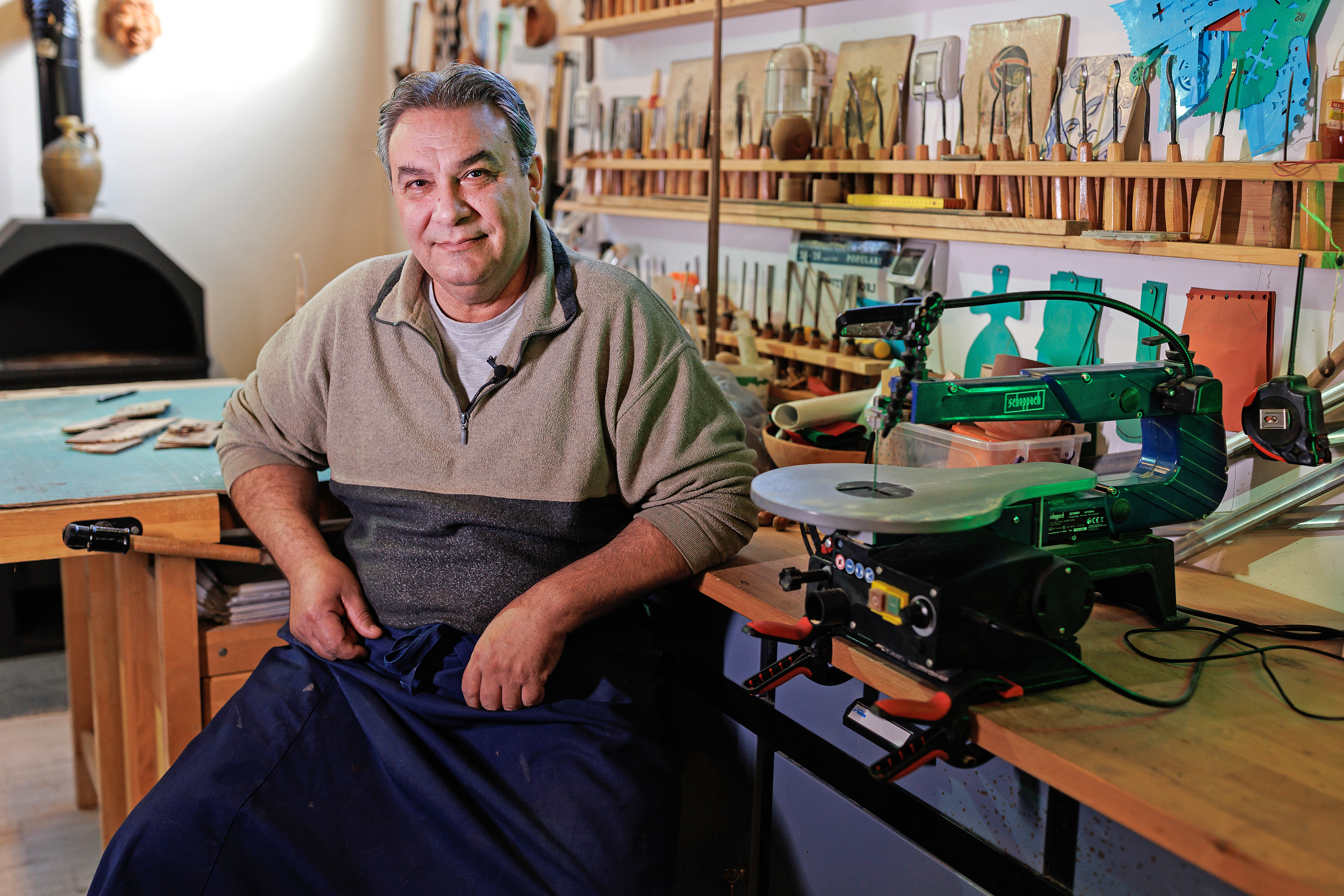 Scenă de atelier cu un bărbat așezat lângă un ferăstrău de traforaj