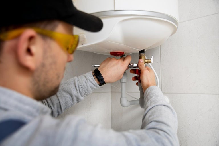 Un instalator conectează un încălzitor de apă.