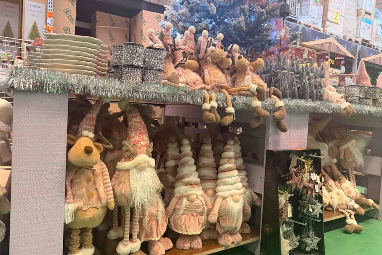 Decoratiuni de Craciun cu figurine reni, spiridusi, podoabe pentru brad si beteala pe un raft intr-un magazin Hornbach.