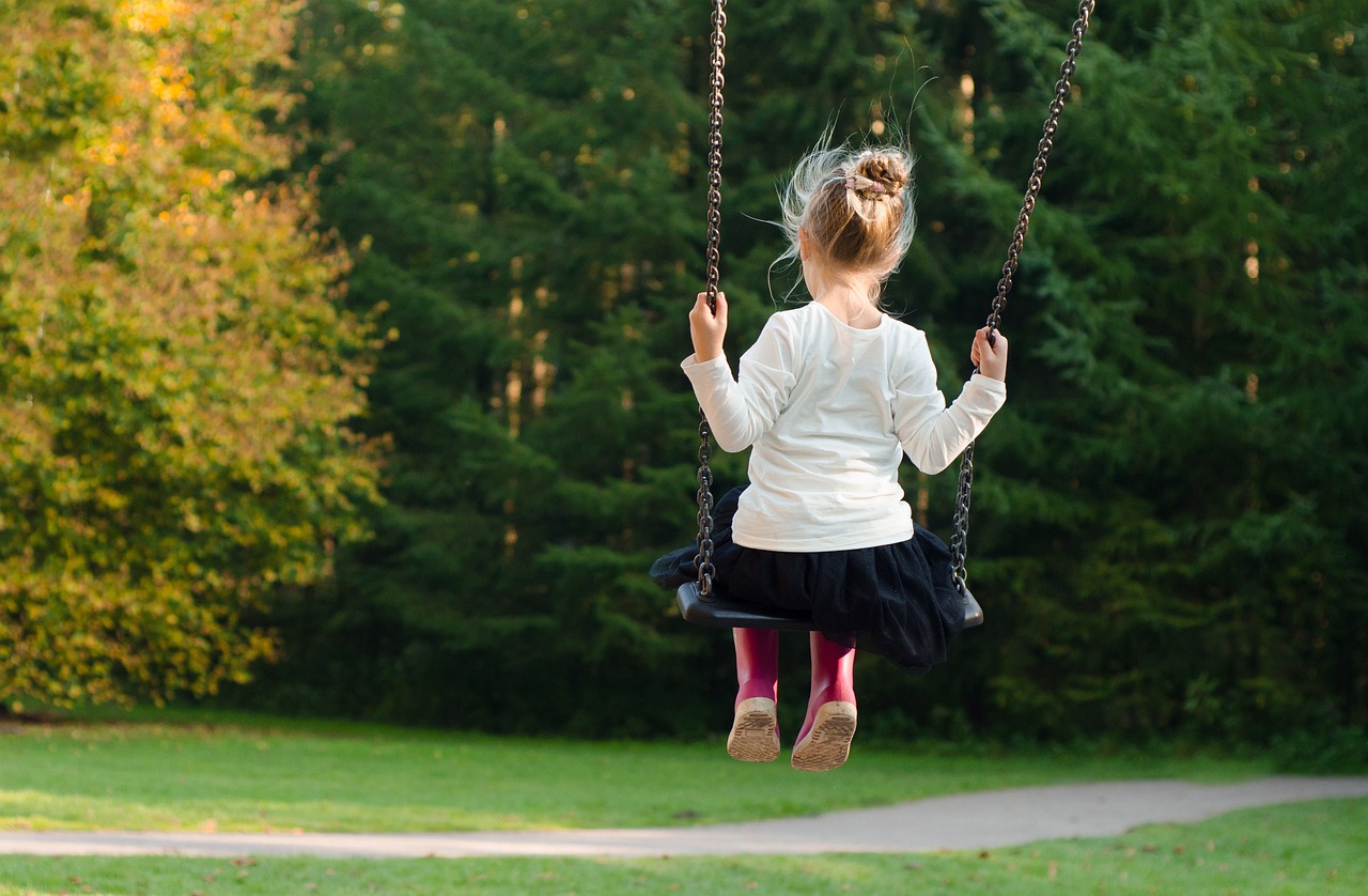 Un copil se dă în leagăn într-un parc.
