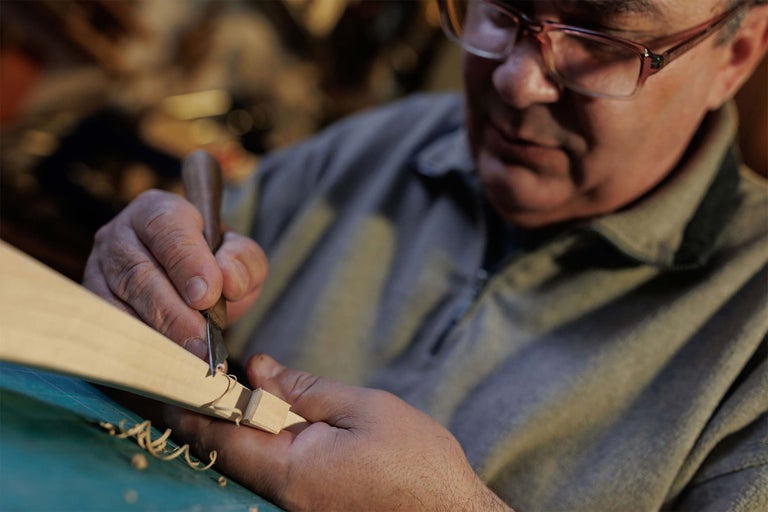 Un bărbat sculptează o bucată de lemn cu o daltă.