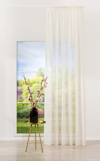 Cameră decorativă cu o perdea de fereastră, o măsuță laterală și o vază cu ramuri de bumbac