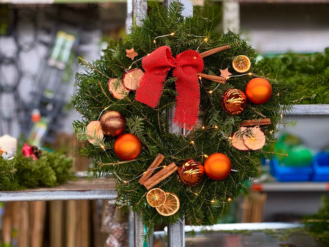 Coroniță de Crăciun cu fundă, globuri, felii de portocală și batoane de scorțișoară ca decorație