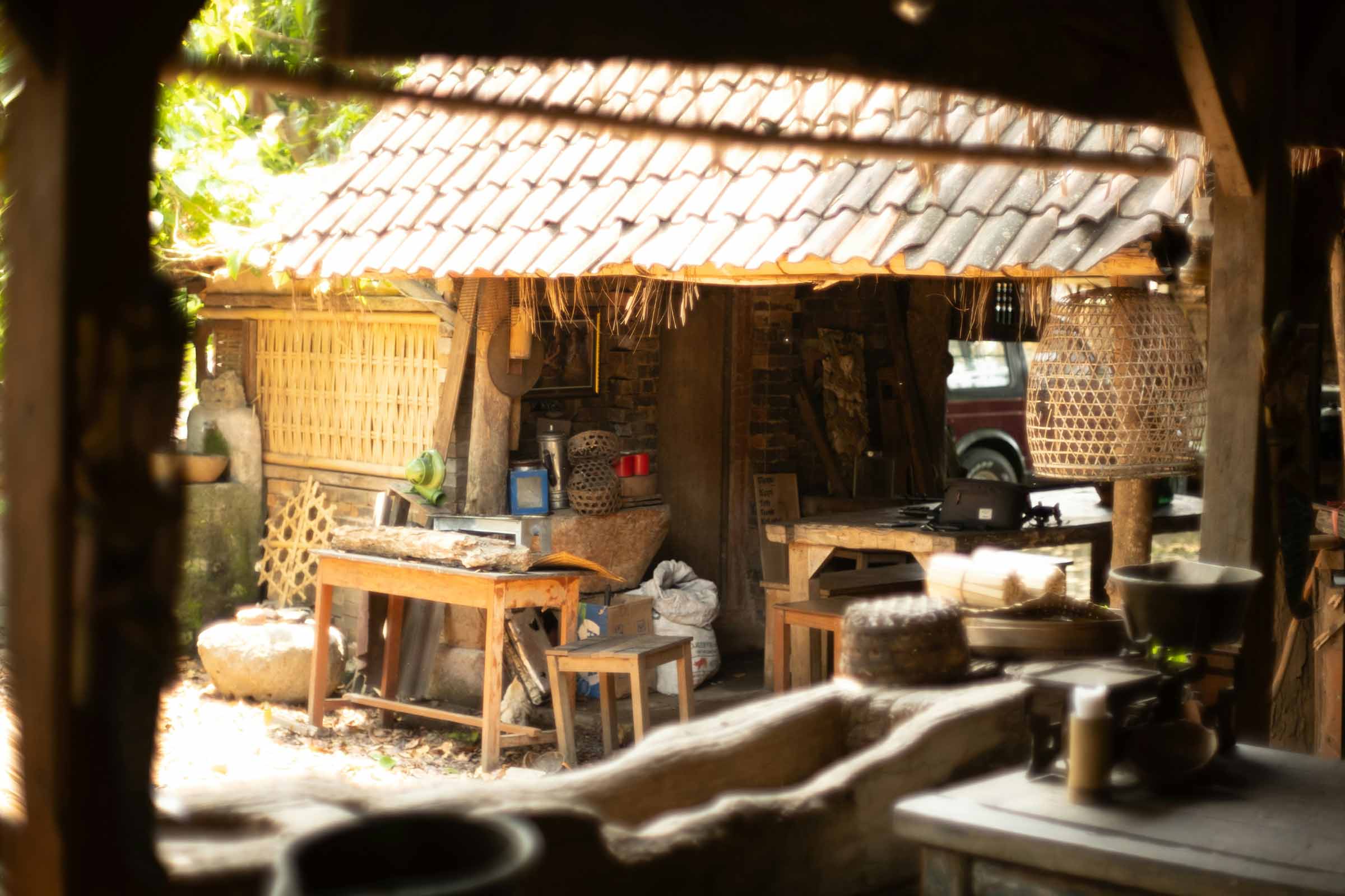 Un atelier rustic cu masă din lemn, unelte și o oală de lut sub un acoperiș de țiglă