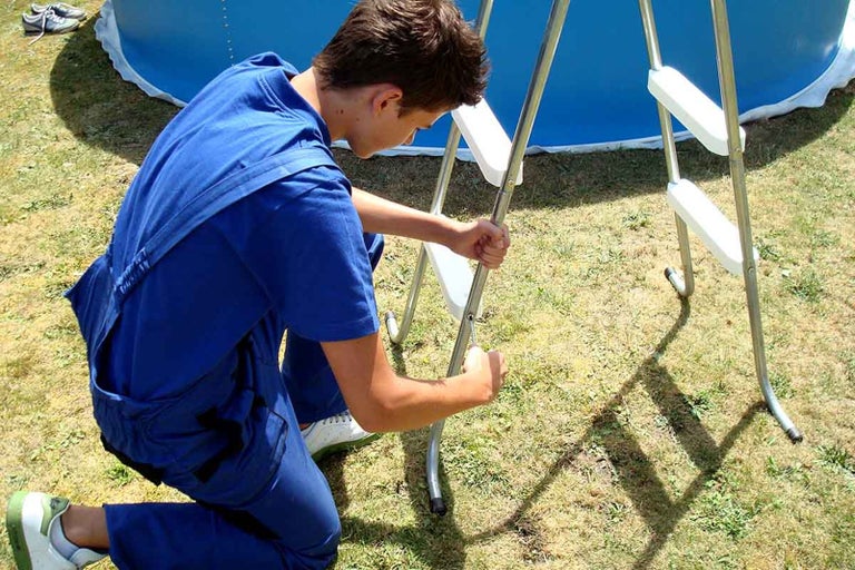 Bărbat montează scară de piscină din metal și plastic la piscină
