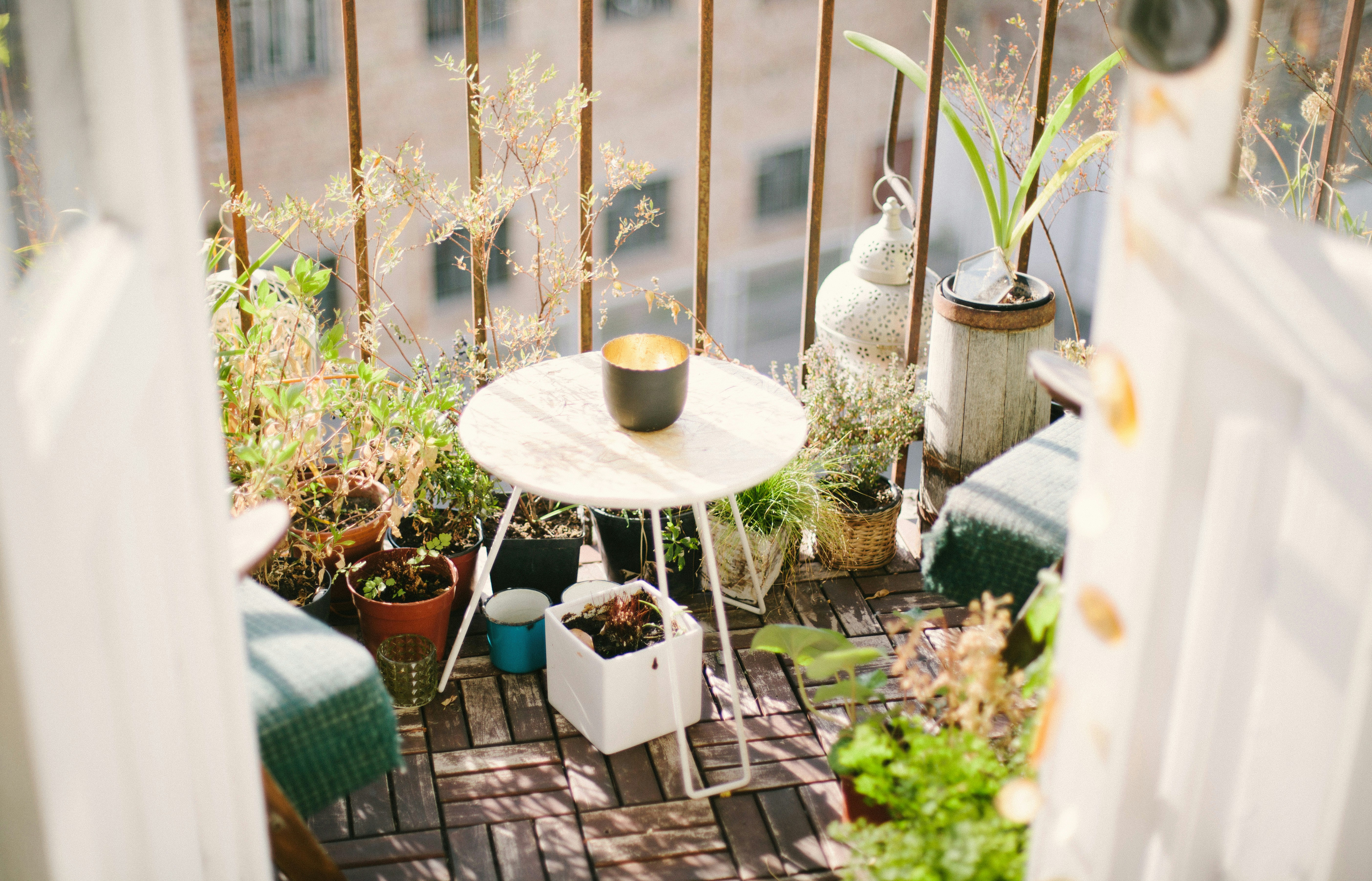 Balcon decorat cu masă, scaune și plante în ghivece.