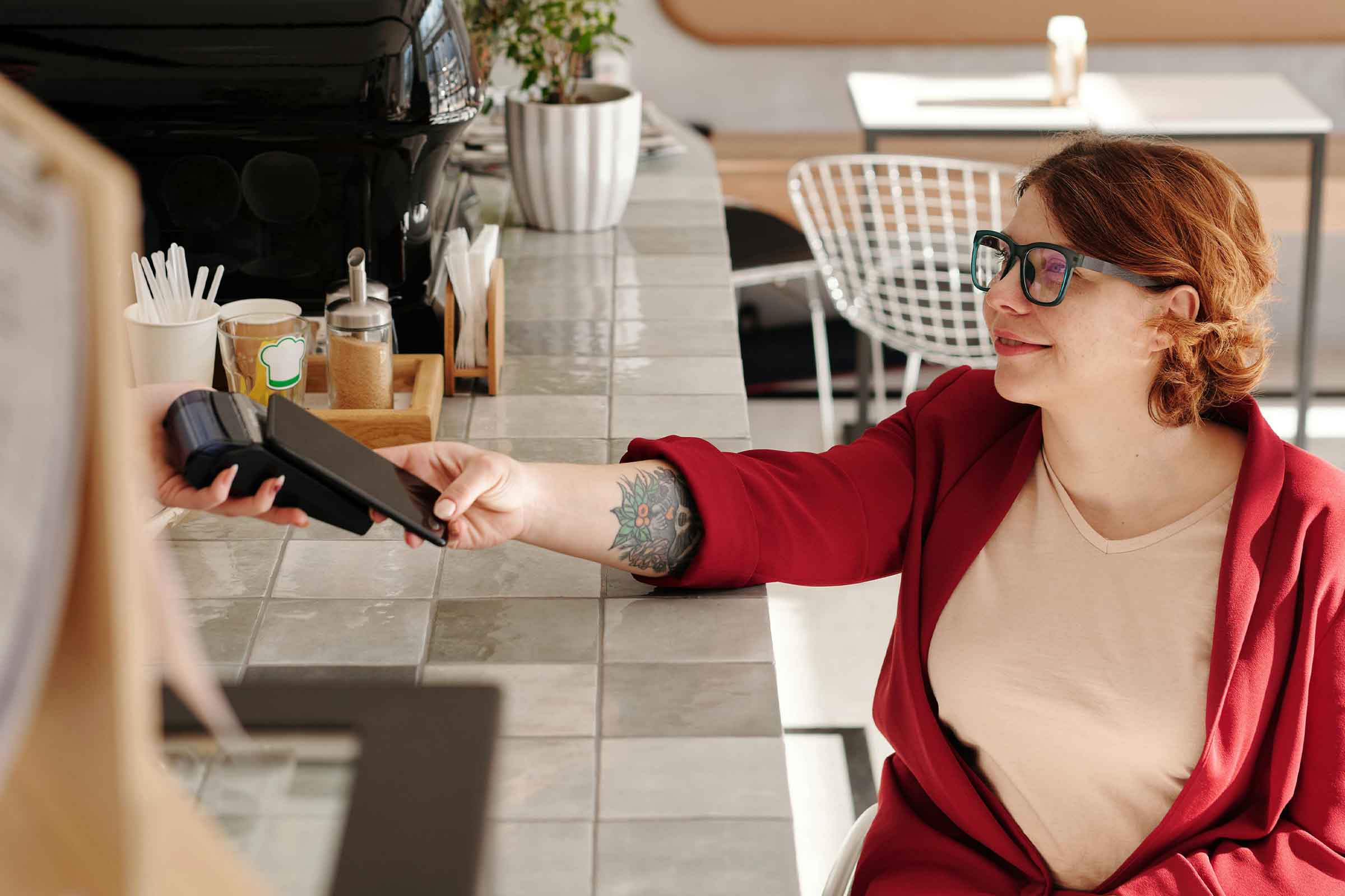 Femeie plătește cu un smartphone la un terminal de plată într-un magazin de vânzare cu amănuntul.