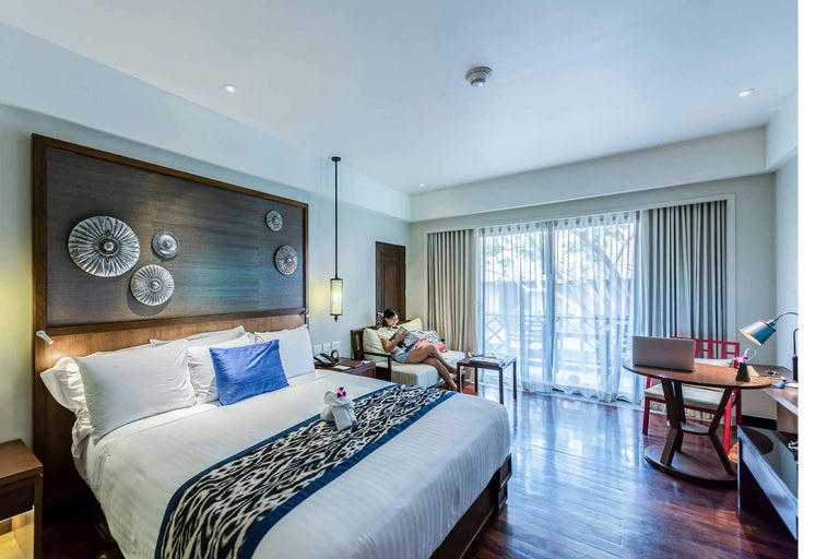 Cameră de hotel luminoasă cu pat, zonă de relaxare și birou