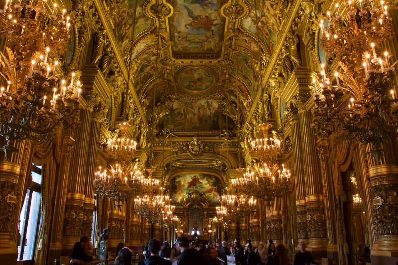 Imagine interior a unei săli de bal opulente, cu picturi pe tavan și numeroase candelabre