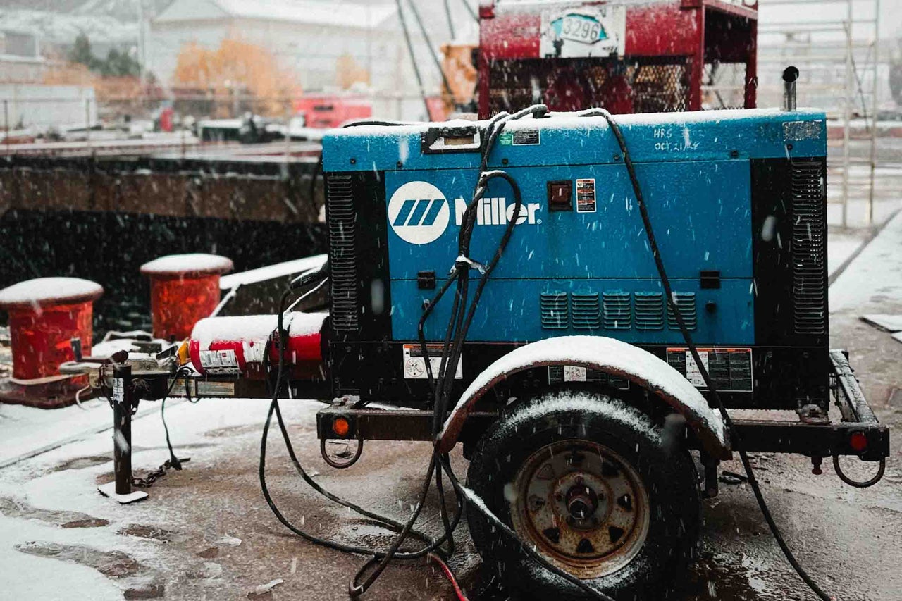 Aparat de sudură și generator Miller pe o remorcă în exterior pe ninsoare. Miller Logo.