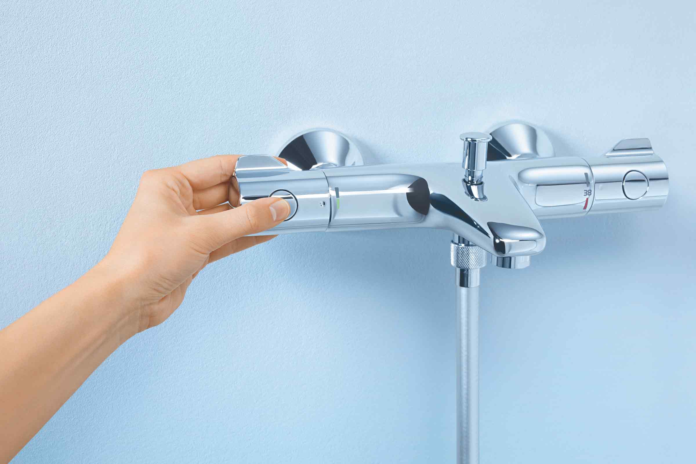 Baterie de duș aplicată pe perete cu termostat și mână care reglează temperatura