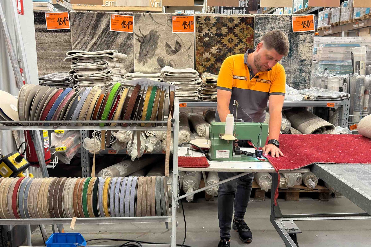 Un angajat Hornbach tiveste un covor cu o mașină de cusut în secțiunea de covoare.