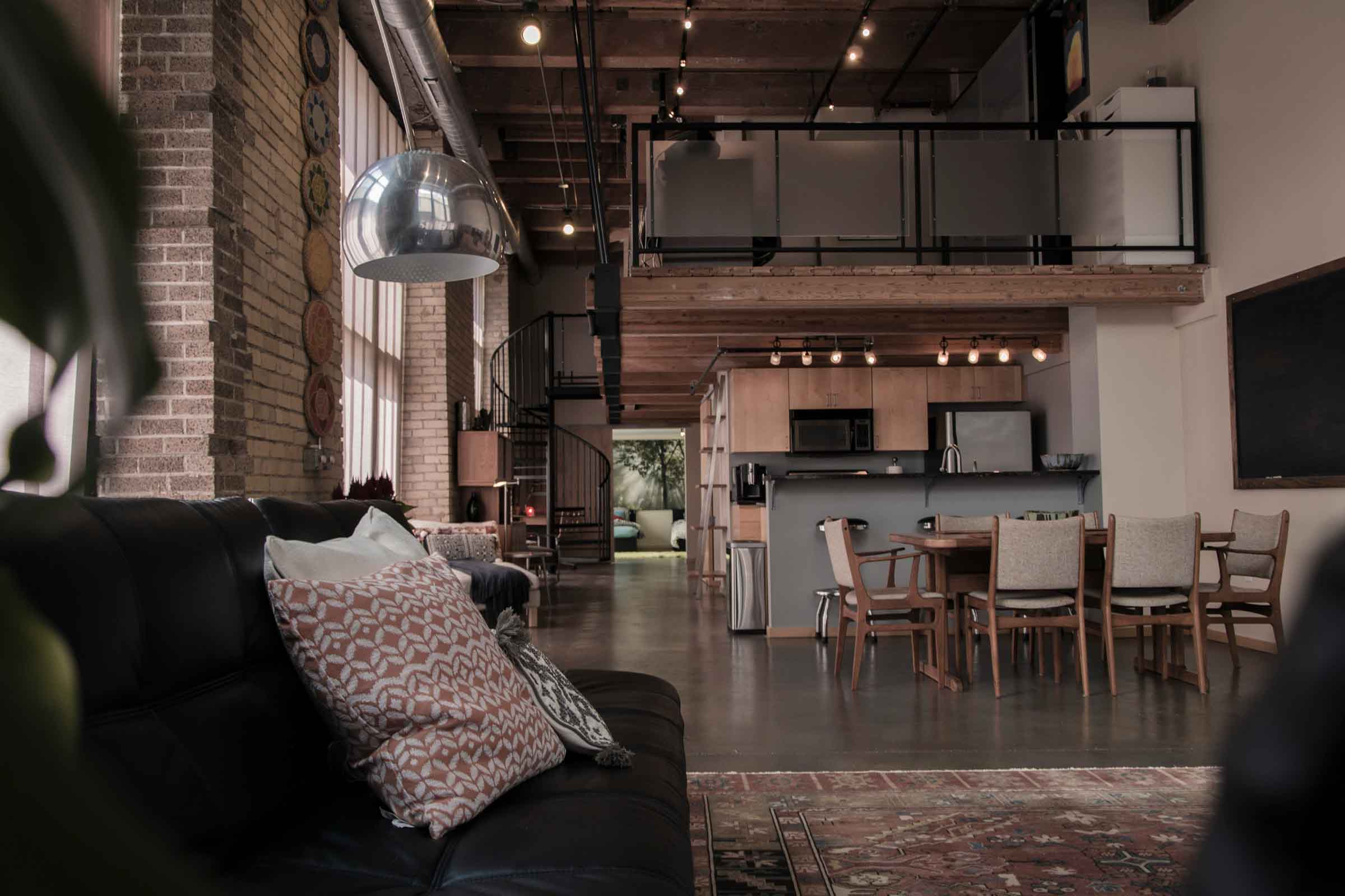Imagine de interior a unei sufragerii cu canapea, masă și bucătărie într-un loft