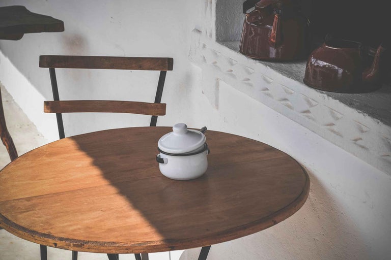 Măsuță rotundă din lemn cu oală albă și capac pe ea
