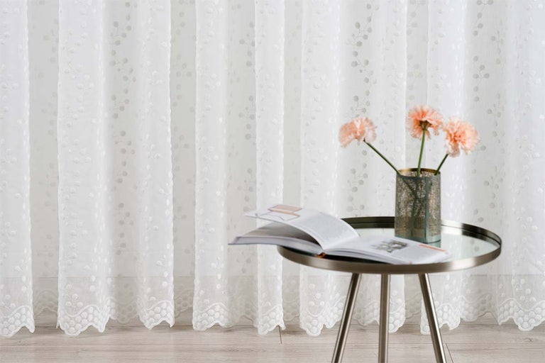 Cortină albă din voal cu model floral lângă măsuța laterală