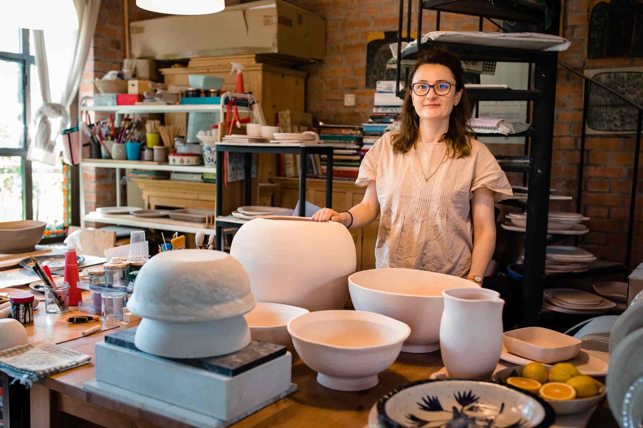 Atelier de ceramică cu produse de olărit precum boluri, ulcioare și vaze pe o masă din lemn