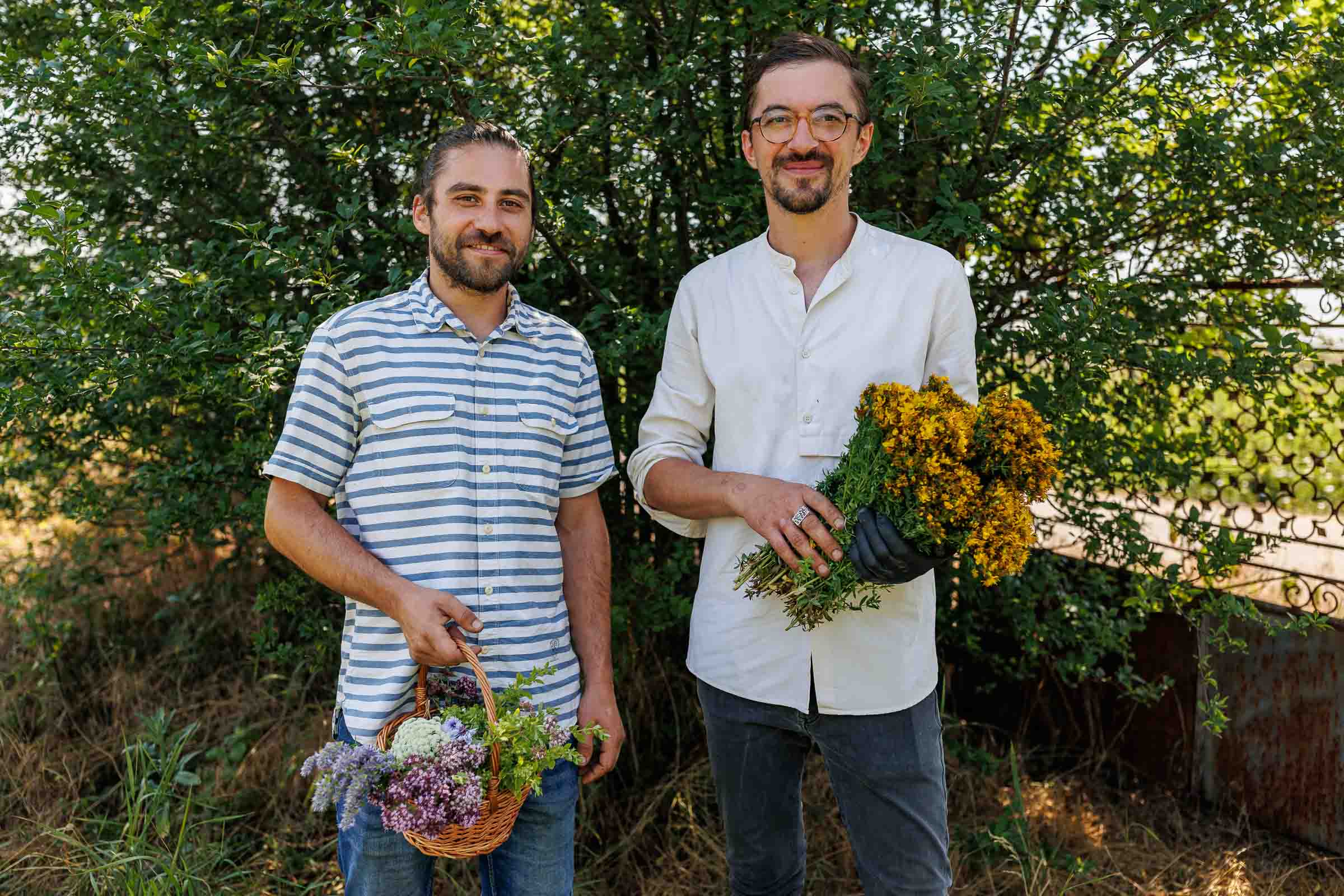 Doi bărbați țin câte un coș și un buchet de flori