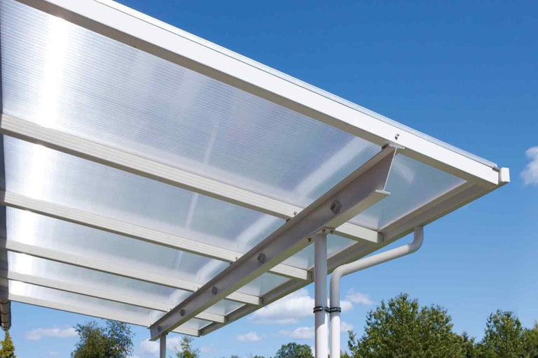 Imagine detaliată a unui carport cu acoperiș transparent și cadru alb.