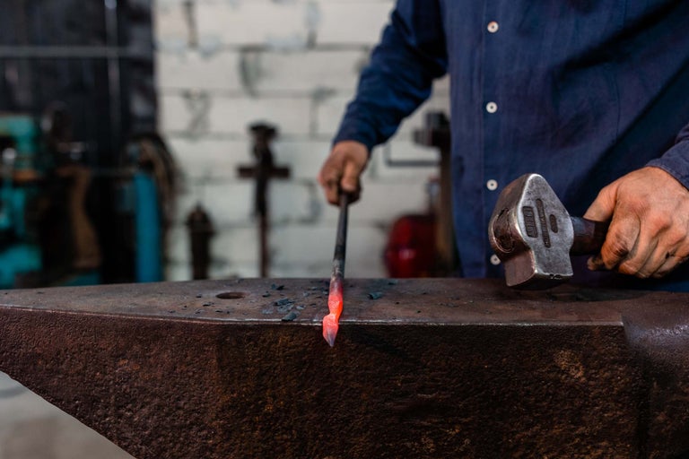 Fierar care lucrează metal incandescent pe o nicovală cu un ciocan