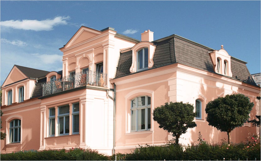 Vedere a unei clădiri rezidențiale cu mai multe etaje, cu fațade decorate și un acoperiș acoperit cu ardezie