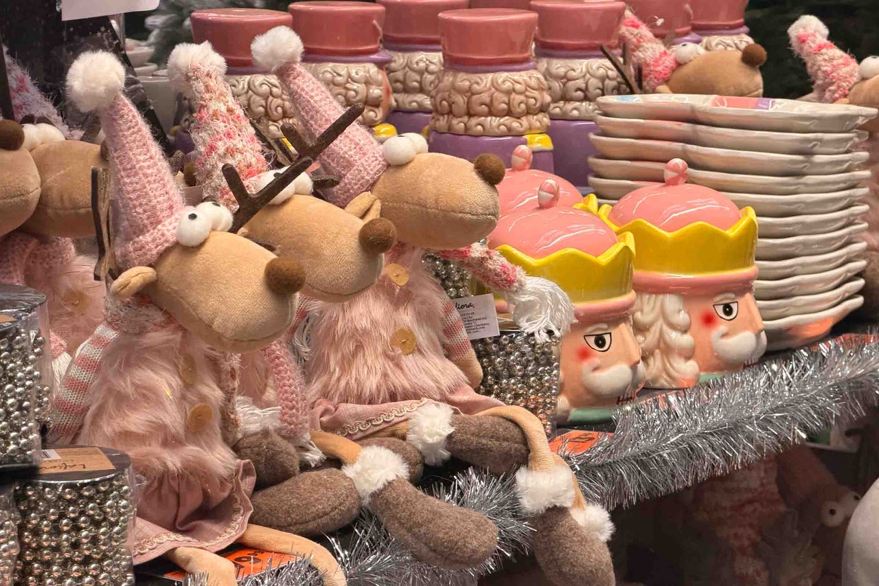 Decoratiuni de Craciun cu figurine reni din material textil si borcane din ceramica in forma de spargator de nuci pe un raft.