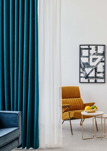 Cameră de zi cu perdele albastre și albe, fotoliu și operă de artă