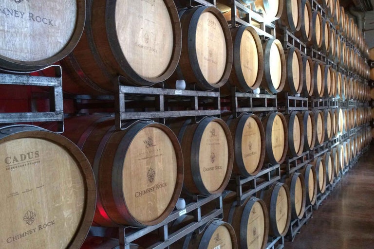 Rând de butoaie de vin pe rafturi metalice într-un depozit