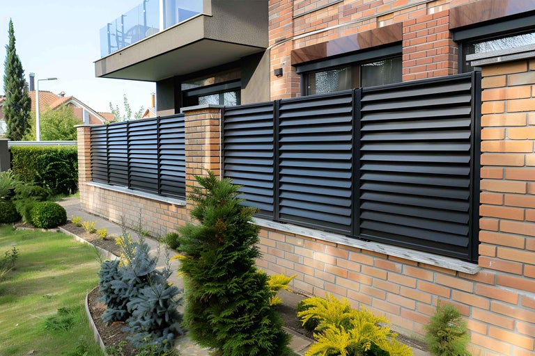 Gard de protecție vizuală cu structură lamelară în fața unei case