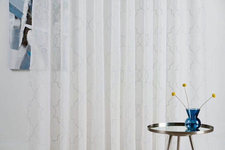 Cortină decorativă albă cu model geometric în sufragerie.