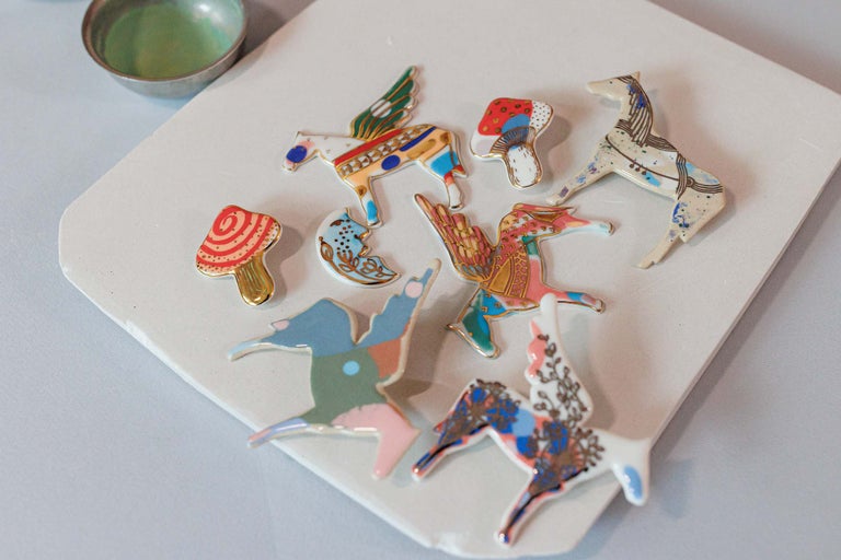 Broșe decorative din email, în diverse forme, pe o suprafață albă