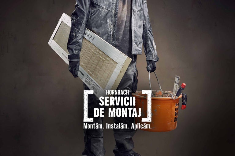 Un meseriaș ține plăci ceramice și o găleată pentru serviciul de instalare Hornbach