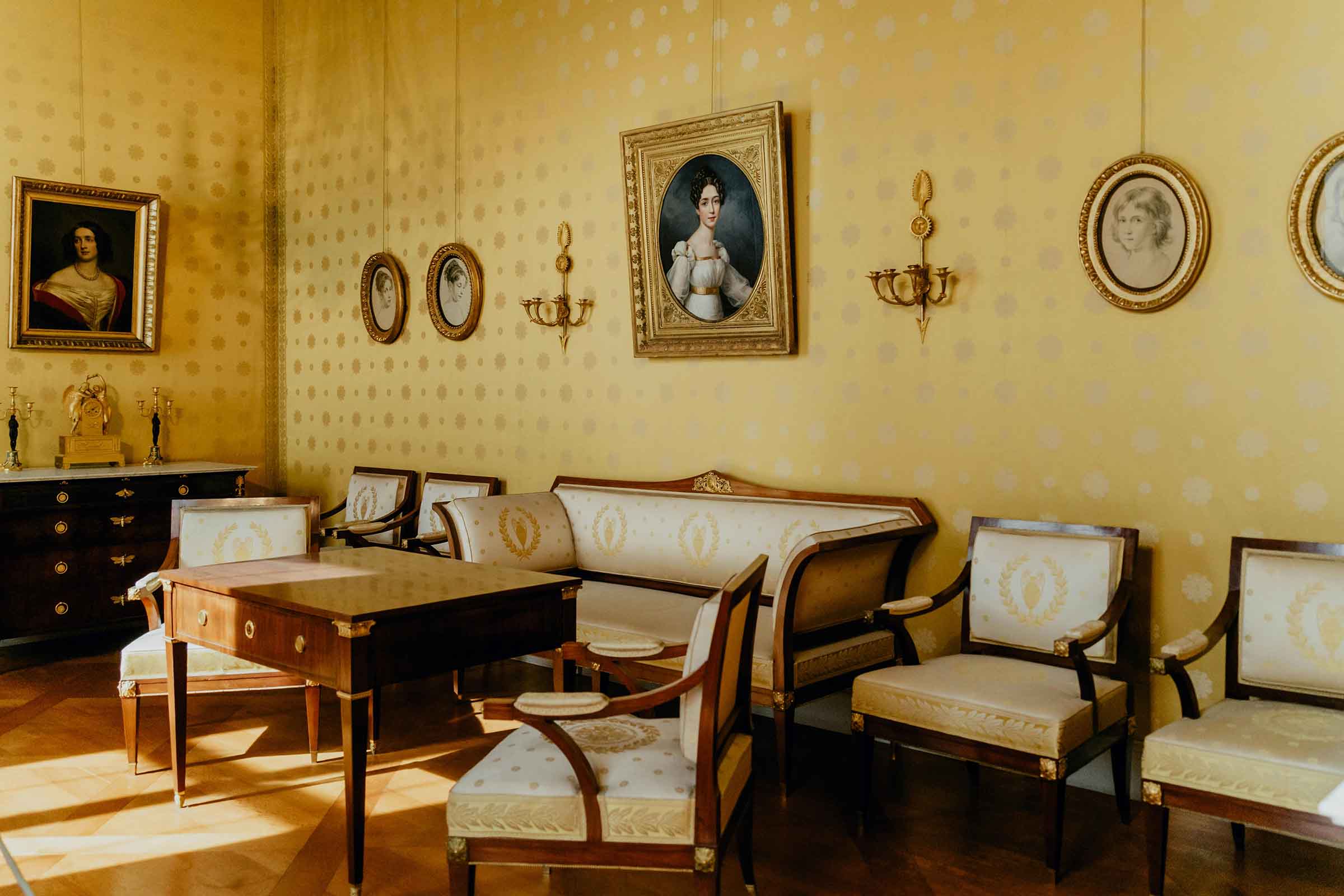 Salon clasic cu tablouri, canapea, fotolii și masă