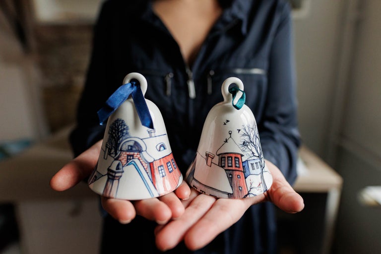 Două clopoței pictați cu panglică sunt ținuți de o persoană.