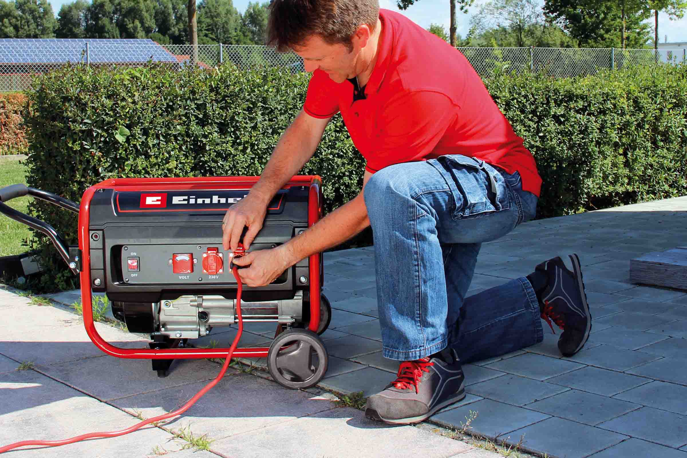 Un bărbat conectează un generator de curent Einhell în exterior.