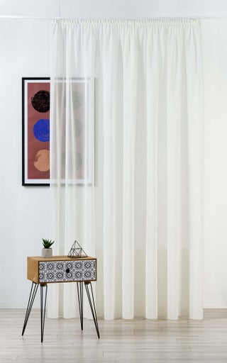 Cortină albă lângă o măsuță și o imagine înrămată
