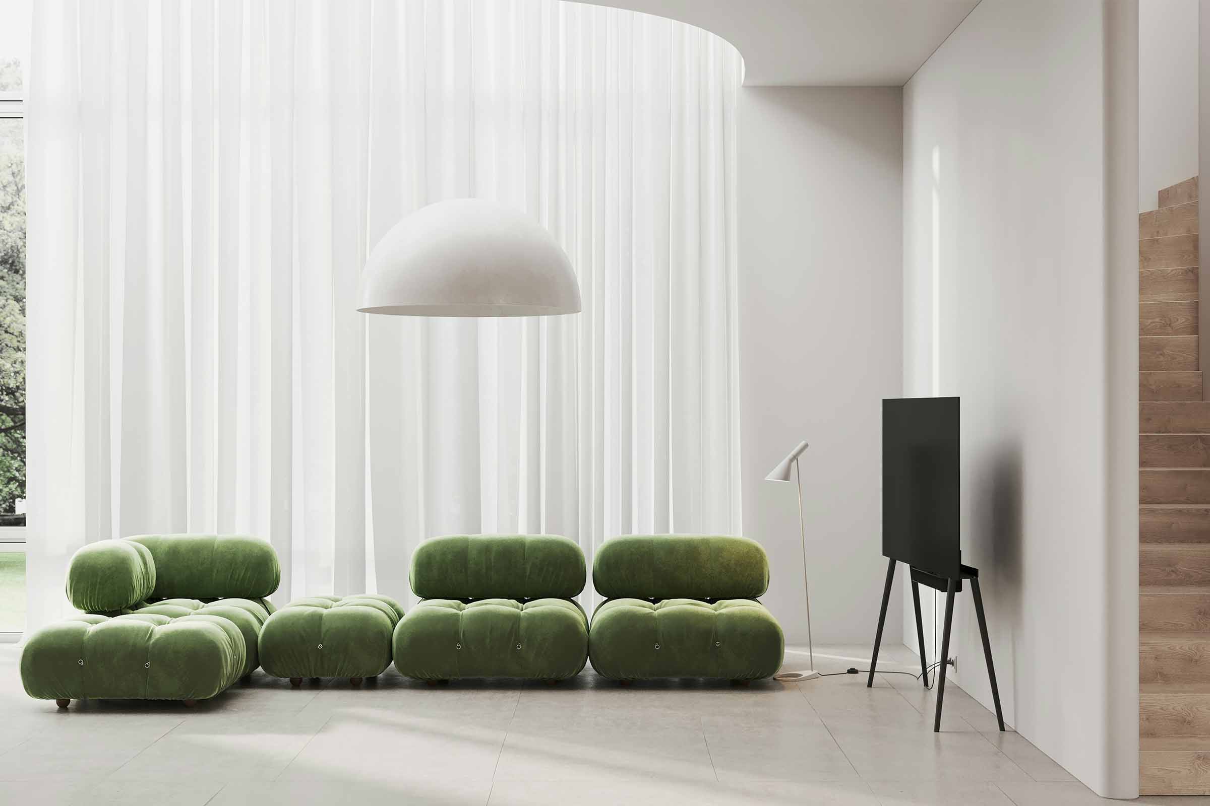 Living luminos cu canapea modulară verde, lampadar și televizor pe trepied.