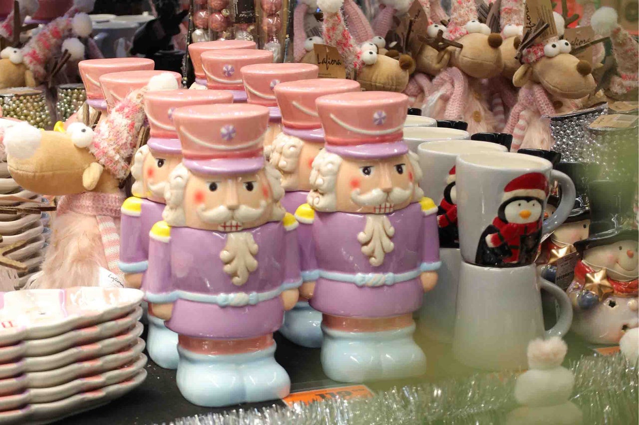 Mai multe căni cu spărgător de nuci din ceramică într-un decor de Crăciun cu alte articole de Crăciun.
