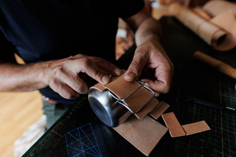 Artizanul prelucrează bucăți de piele pe o cană metalică pentru prelucrarea pielii.