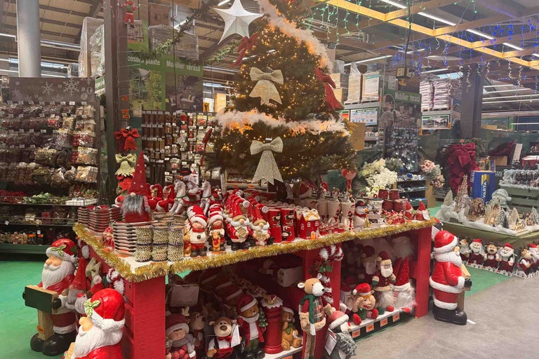 Expoziție de vânzare de Crăciun într-un magazin Hornbach, cu brad de Crăciun, figurine decorative, Moși Crăciun și decorațiuni festive.