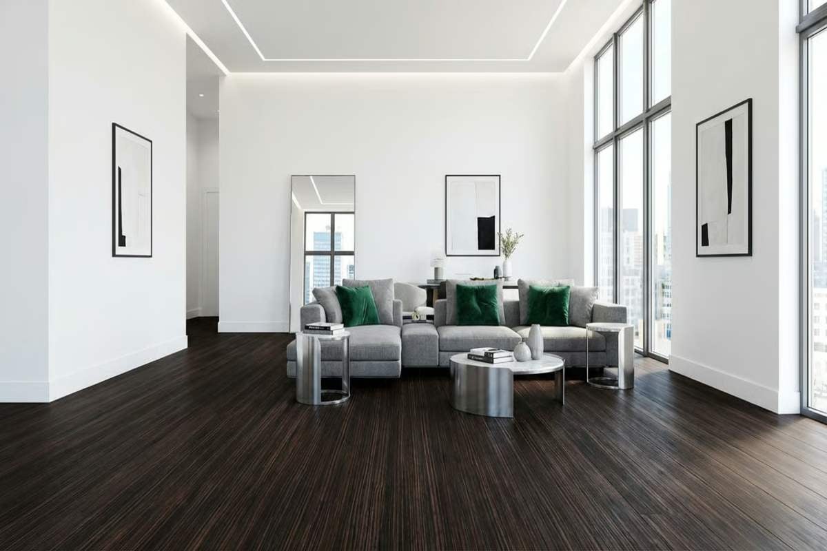 Cameră de zi luminoasă cu canapea gri, perne verzi și podea din lemn închis la culoare