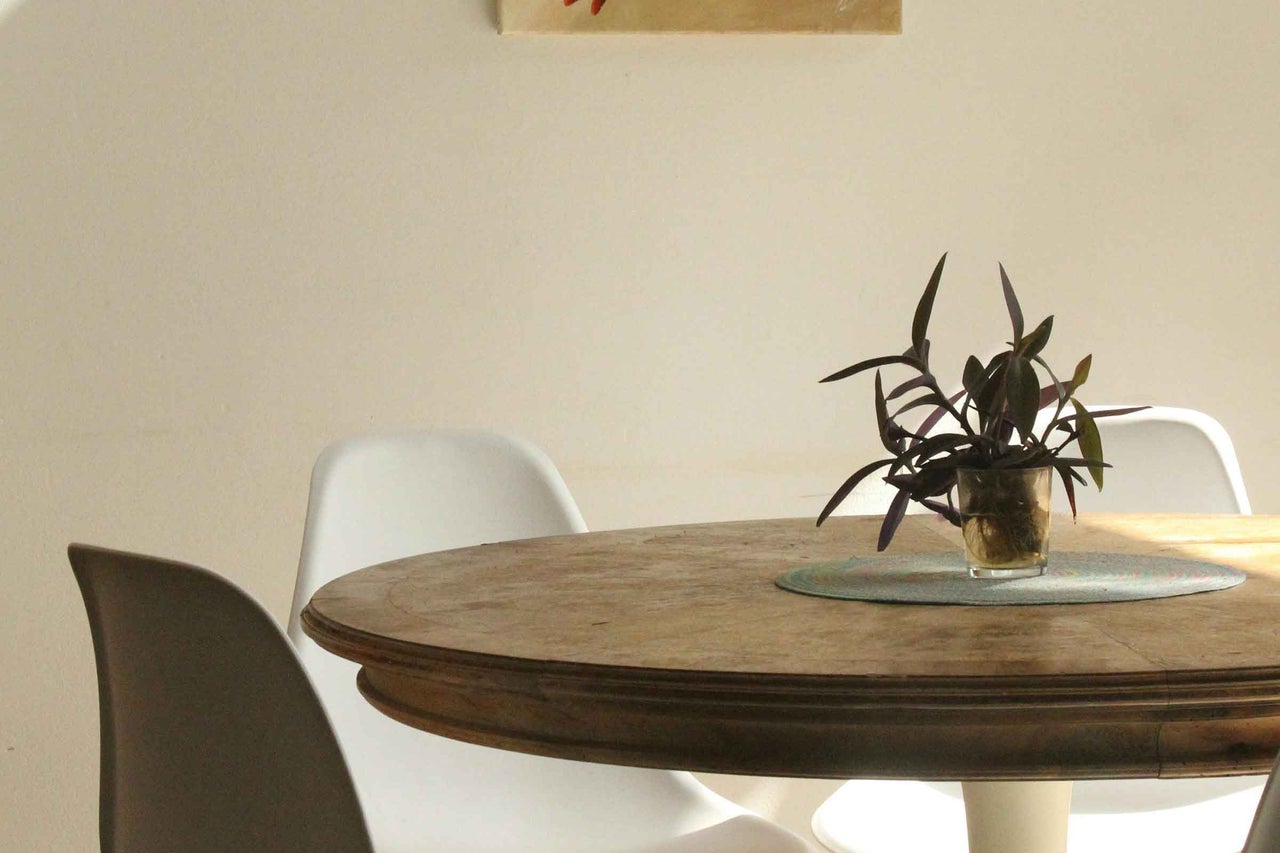 Scenă de luat masa cu masă rotundă din lemn, scaune și plantă în ghiveci pentru o atmosferă luminoasă și primitoare.