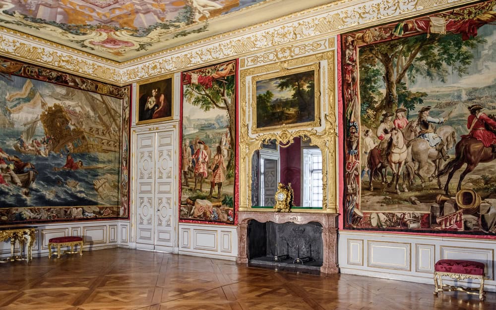 Interior cu tapiserii, picturi, oglindă și șemineu