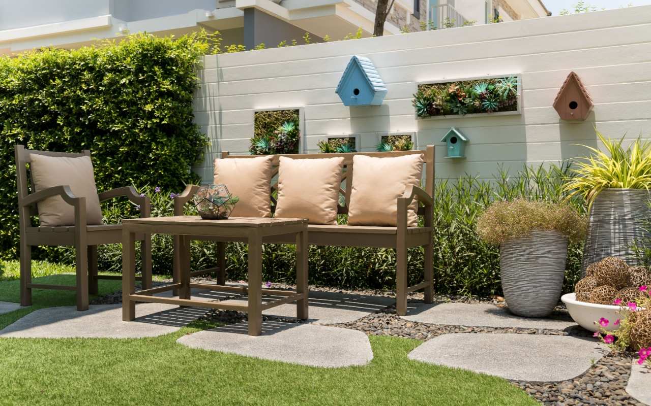 Set de mobilier de grădină cu bancă, scaun și masă pe gazon cu decorațiuni precum jardiniere și case pentru păsări
