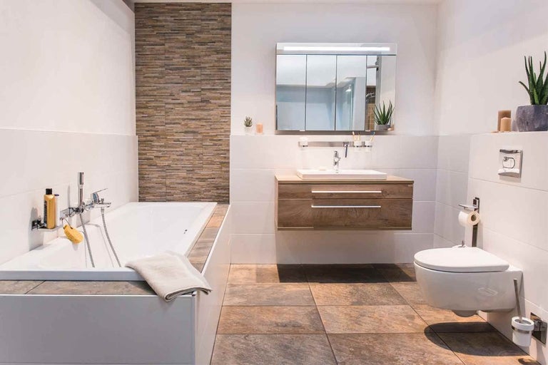 Baie modernă cu cadă, chiuvetă, dulap cu oglindă și toaletă