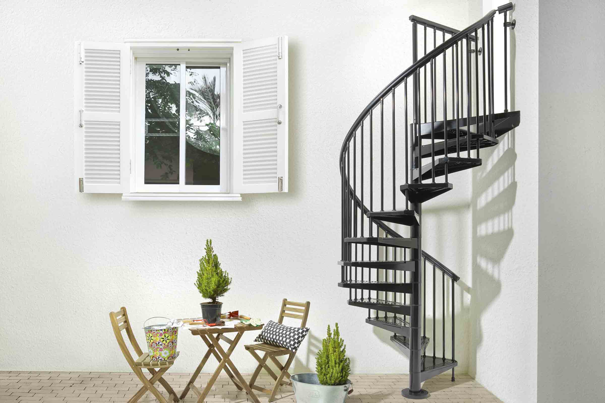 Vedere exterioară cu scară spiralată metalică, masă și fereastră