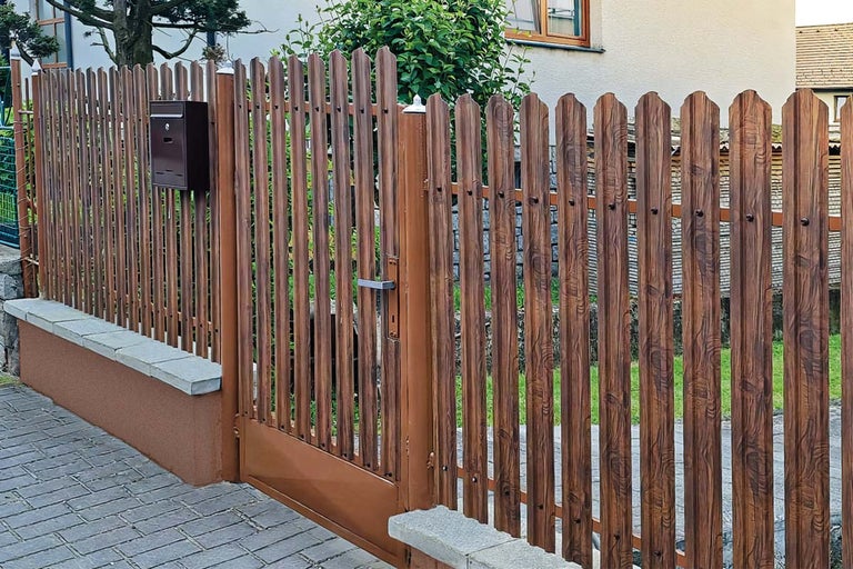 Gard de grădină și poartă cu aspect de lemn cu șipci verticale montate pe un soclu zidit cu cutie poștală.
