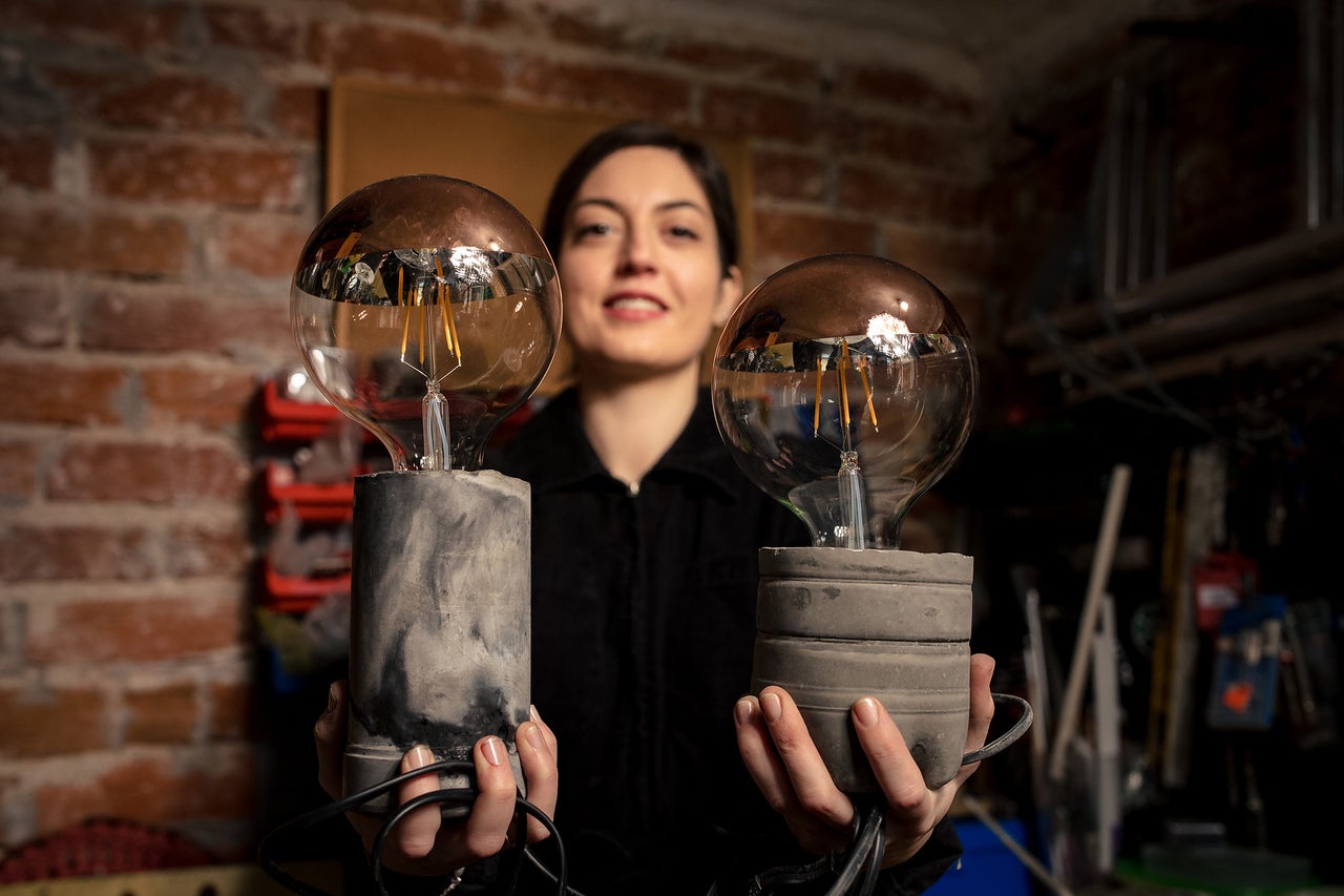Femeie ținând două becuri decorative Edison cu bază de beton.